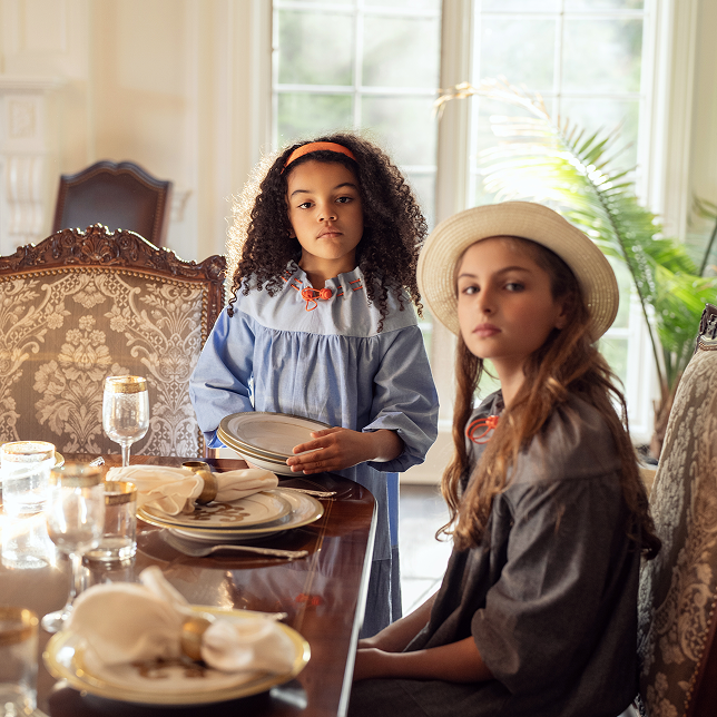 Girls in elegant Puvu Pior® dresses at a formal dining table, showcasing a high-end, classic lifestyle aesthetic.