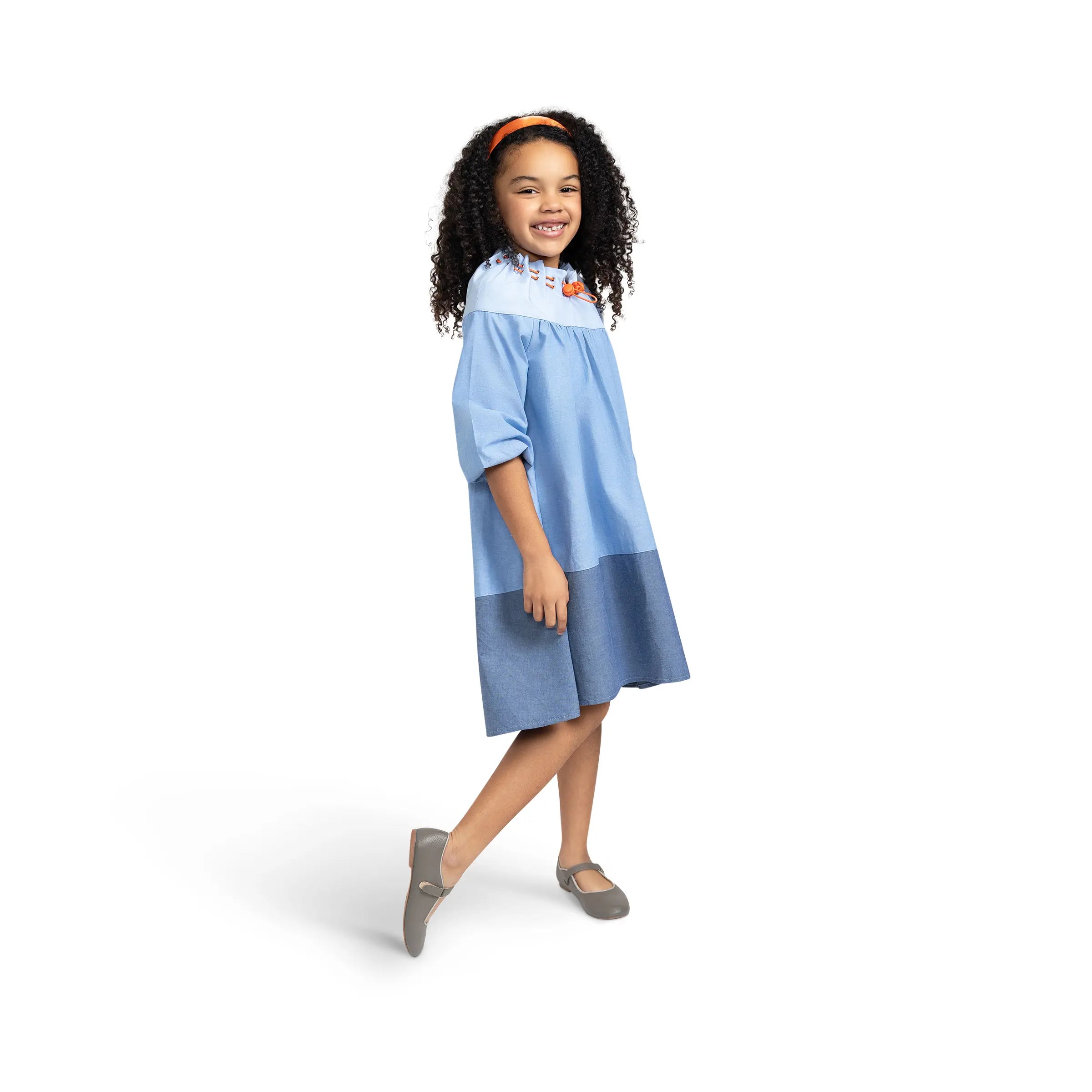 Smiling girl modeling Puvu Pior® light chambray dress, highlighting the comfortable, flowy fit and two-tone colorblock.
