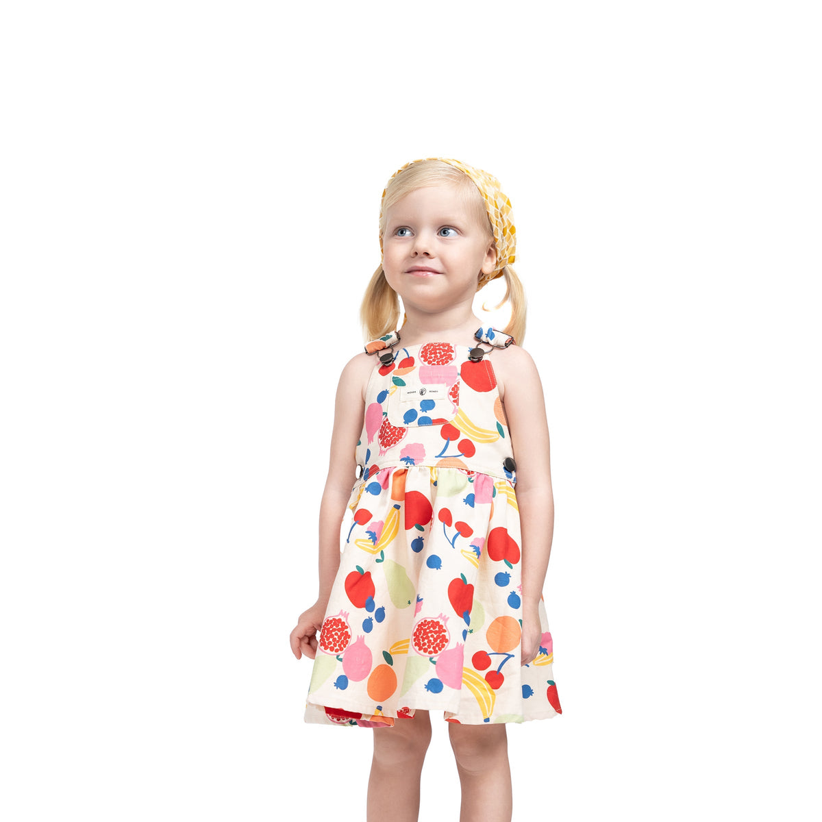 Close-up of Puvu Pior® fruit print pinafore, highlighting the vibrant multi-color print and strap buckle details.