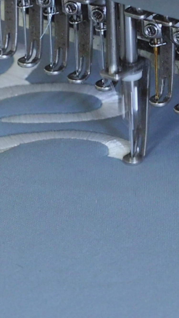 A close-up, high-definition video of an industrial embroidery machine precisely stitching the Puvu Pior signature logo and the PP emblem into premium fabric, showcasing the brand's commitment to artisanal craftsmanship and technical detail.